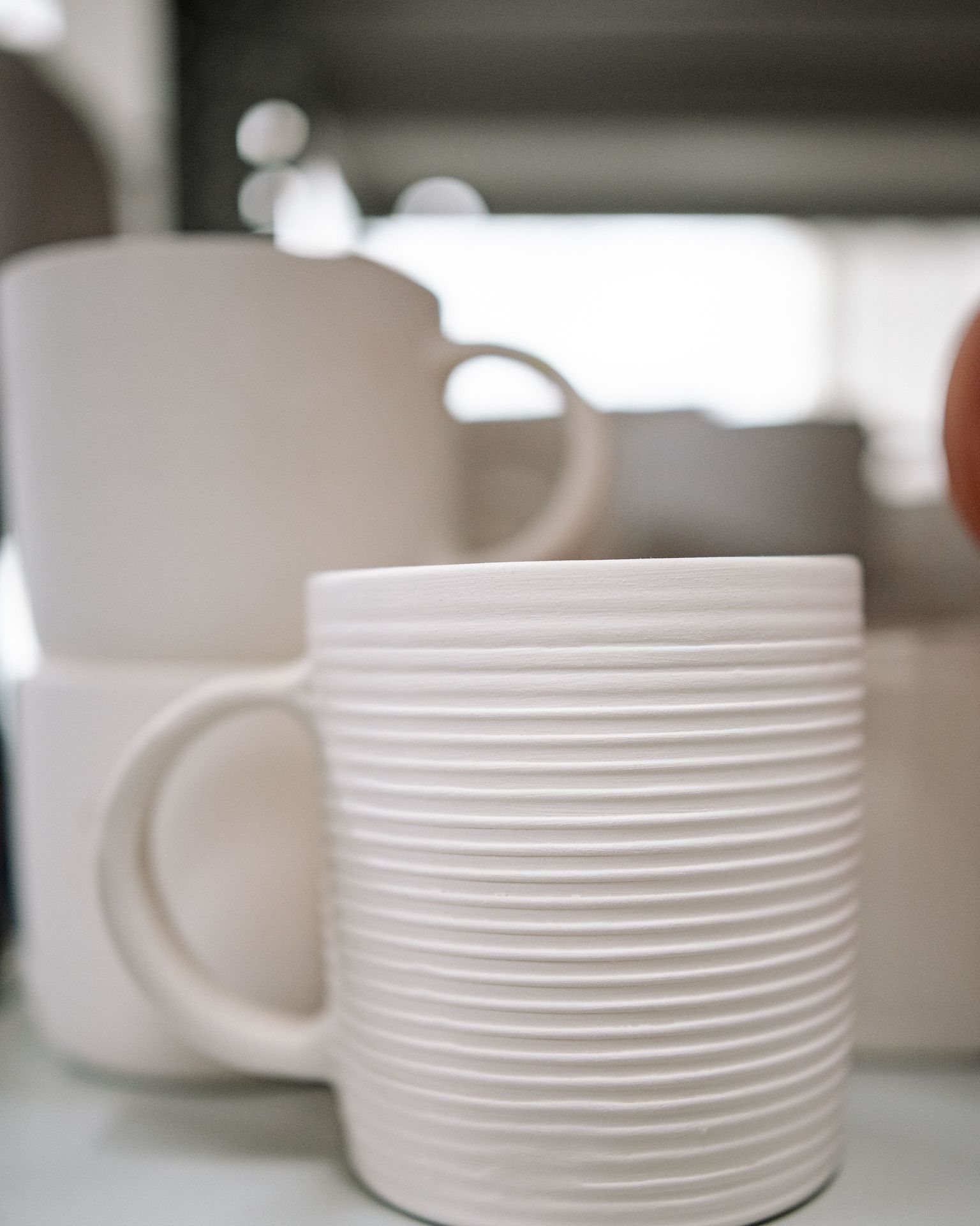 A mug after the first firing, pale and matt.